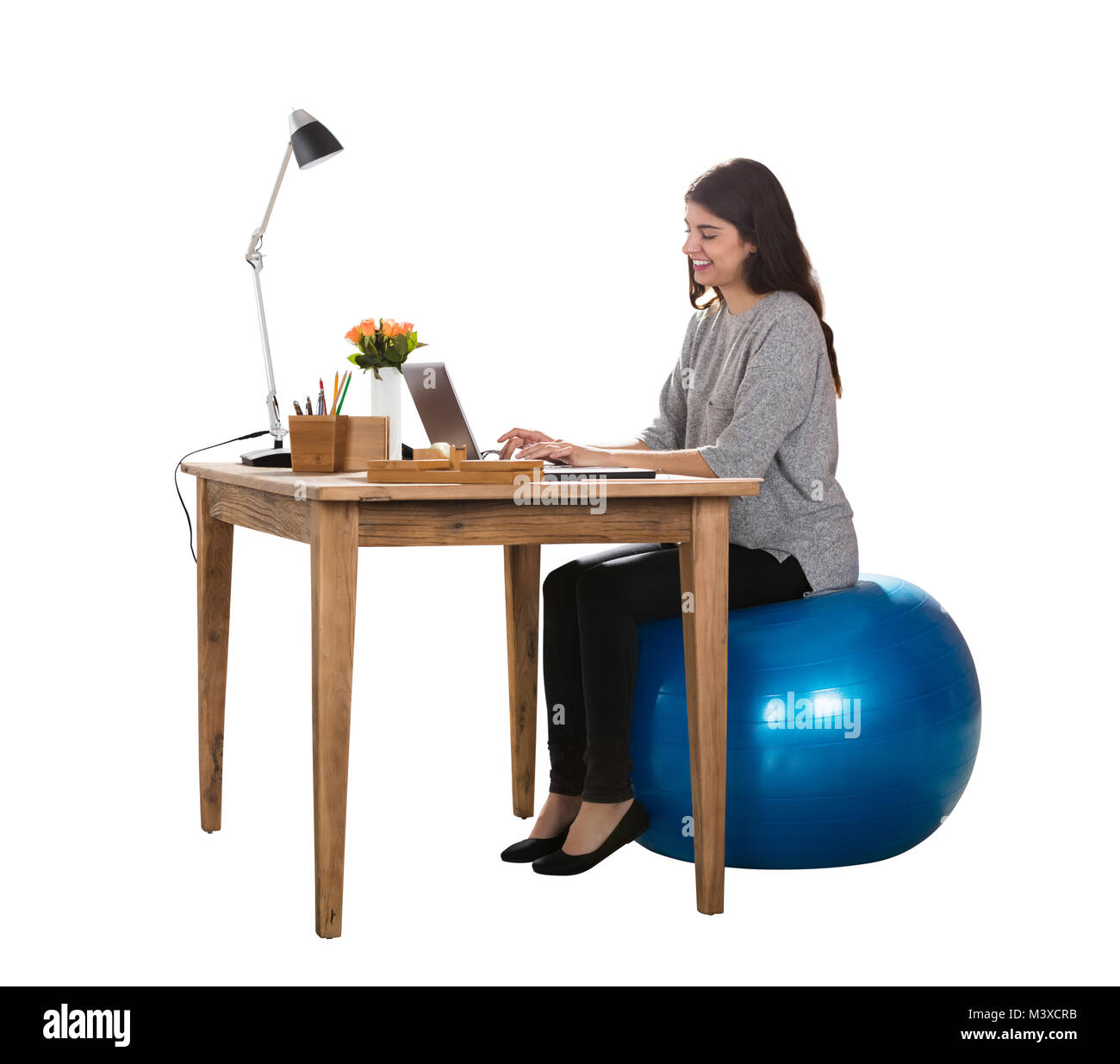 Felice giovane donna seduta sulla sfera di Pilato lavorando sul computer portatile Foto Stock