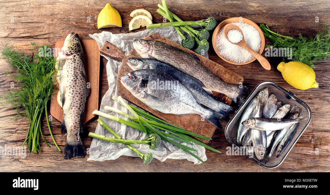 Il pesce fresco e gli ingredienti per cucinare o sfondo di legno. Vista dall'alto. Foto Stock