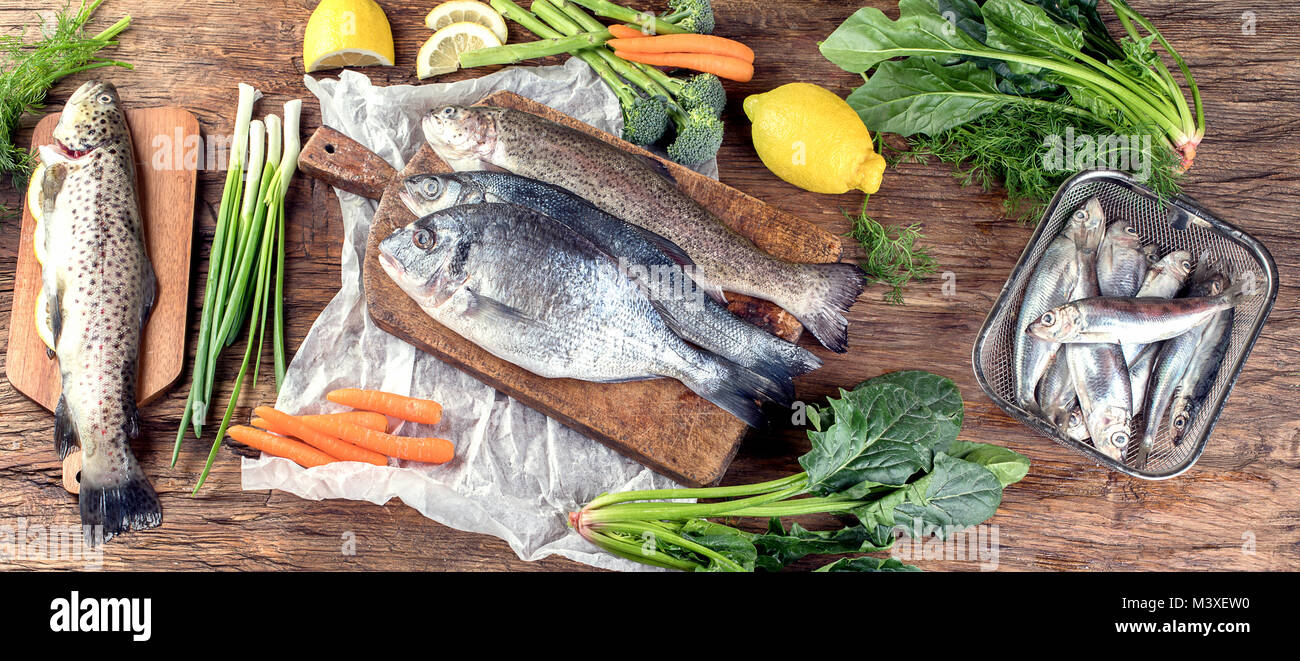 Il pesce fresco e gli ingredienti per cucinare o sfondo di legno. Vista dall'alto. Foto Stock