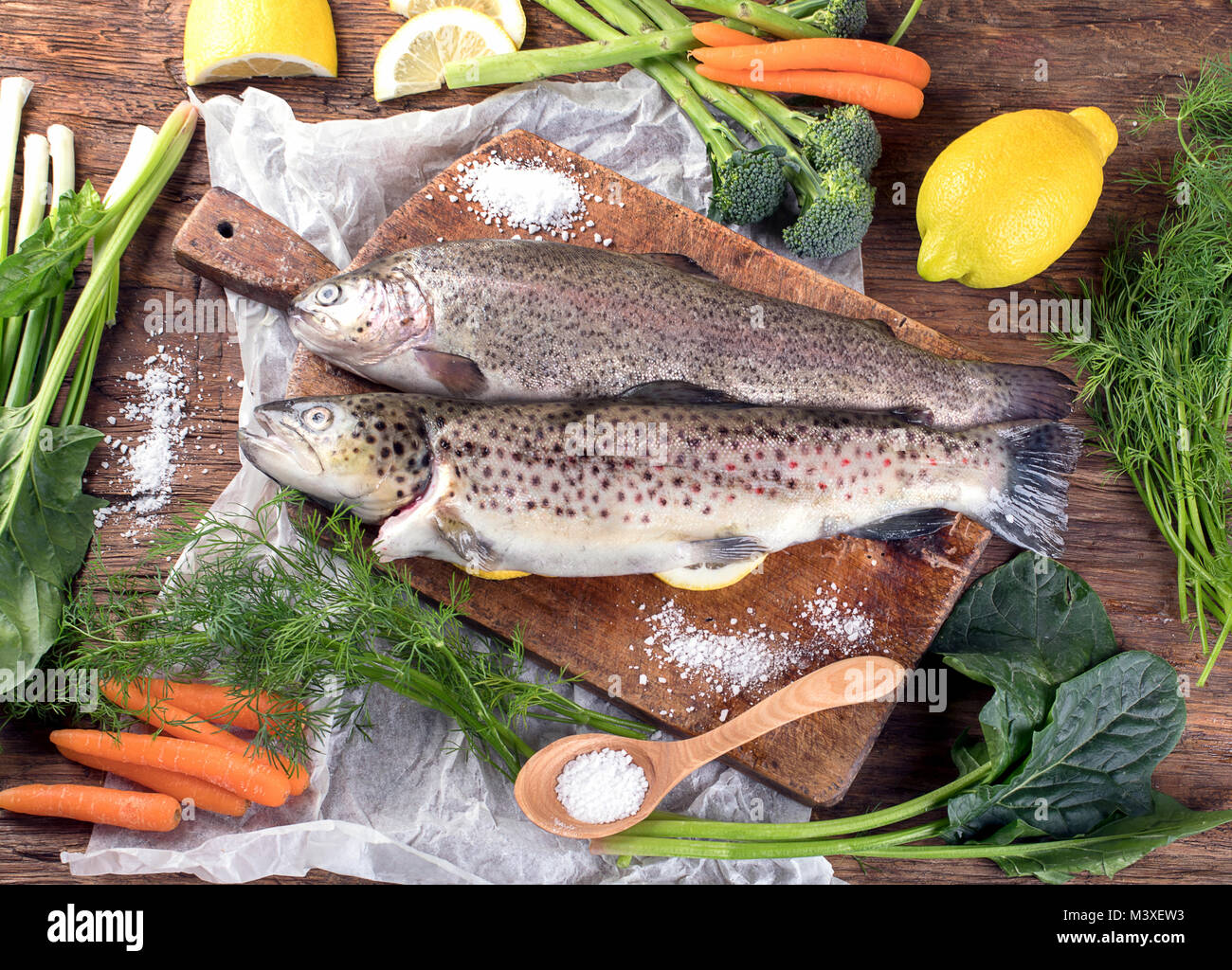Il pesce fresco e gli ingredienti per cucinare o sfondo di legno. Vista dall'alto. Foto Stock