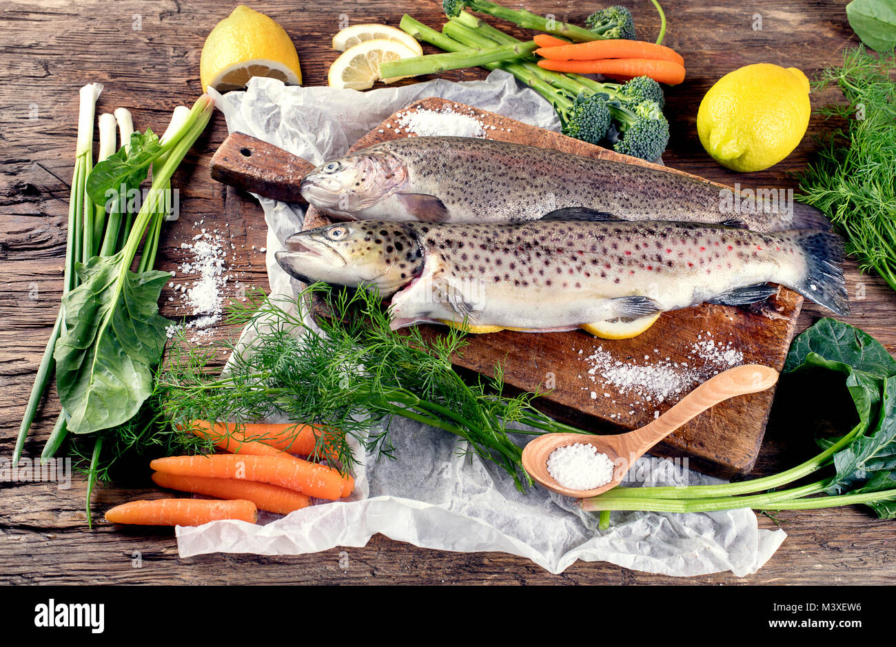 Il pesce fresco e gli ingredienti per cucinare o sfondo di legno. Vista dall'alto. Foto Stock