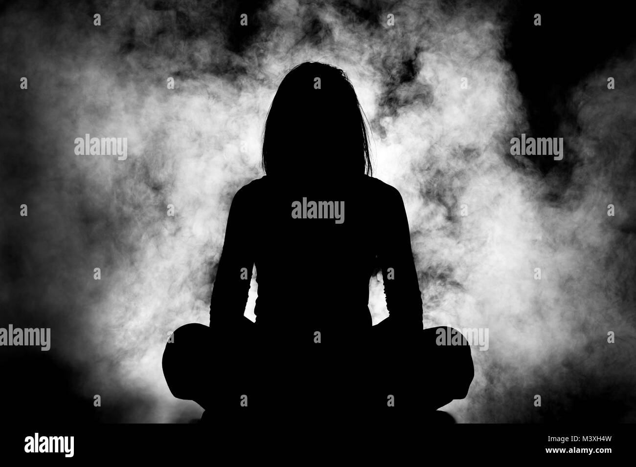 Silhouette di una ragazza meditando contro il fumo bianco sullo sfondo Foto Stock