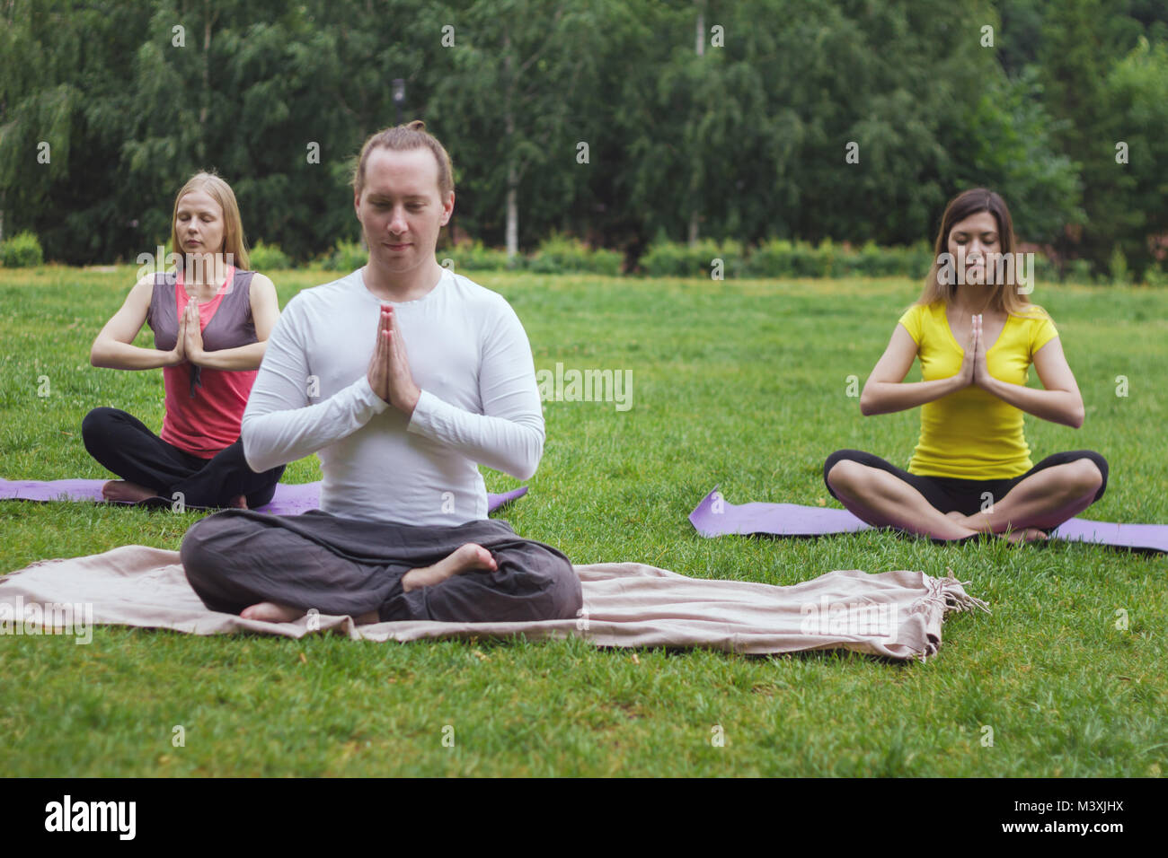 Lo Yoga sportivi nel parco - gli atleti in lotus pongono Foto Stock