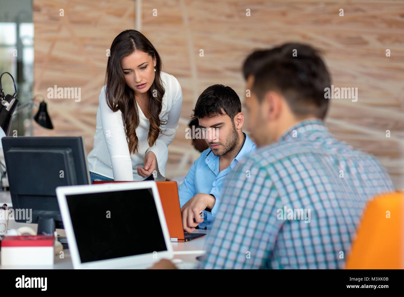 Piacevole sorridente giovani colleghi per discutere il progetto in un moderno ufficio di avvio Foto Stock