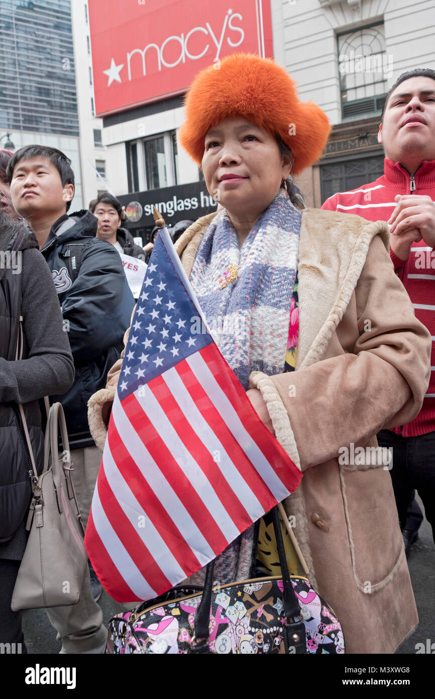 Un Cinese donna americana tenendo una bandiera americana a un pro immigrazione ant-Trump al rally di Herald Square a Manhattan, New York City. Foto Stock