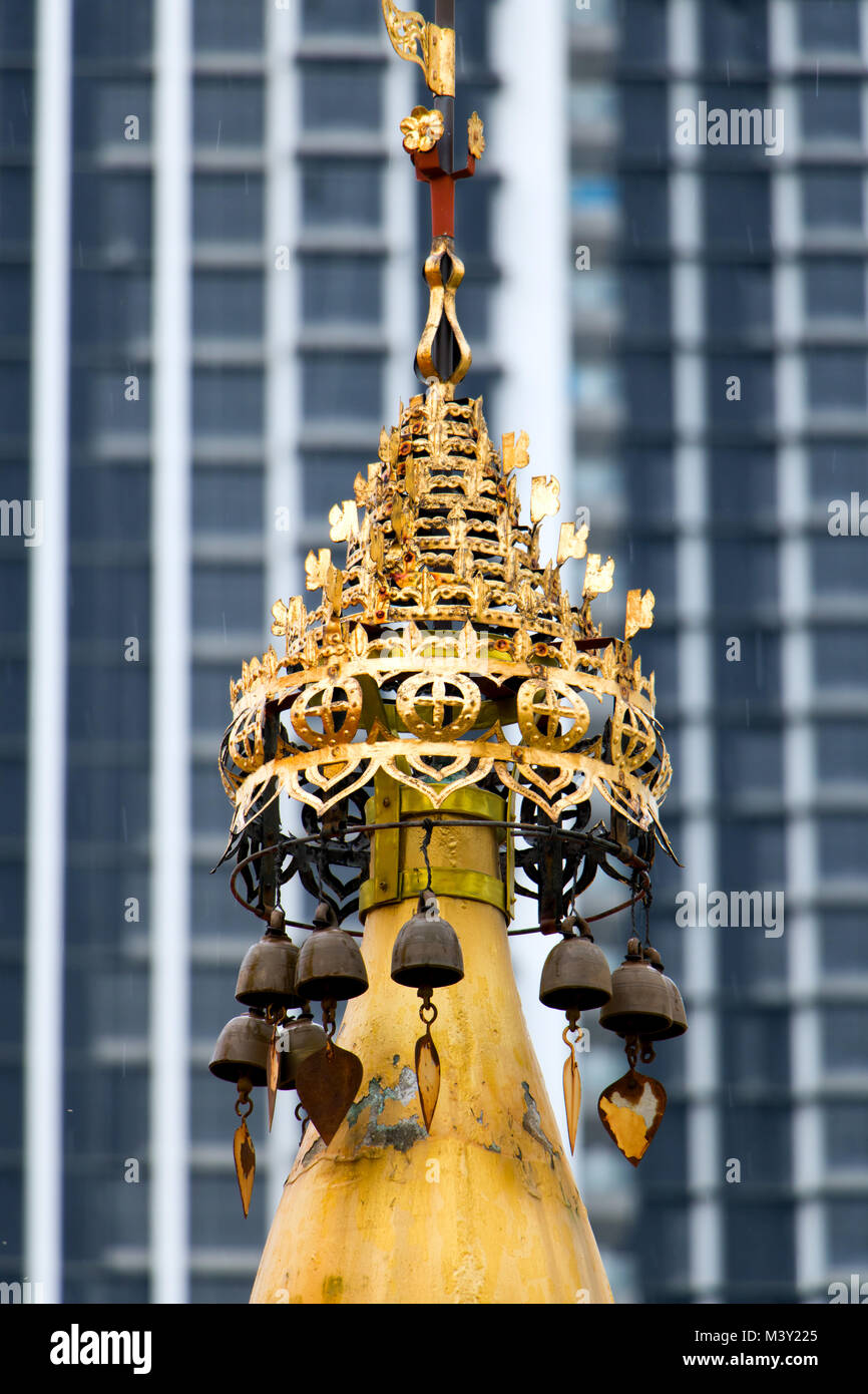 Golden decorativi torretta in un monastero buddista Dhammikarama Tempio birmano Penang, sullo sfondo di un grattacielo di facciata. Foto Stock