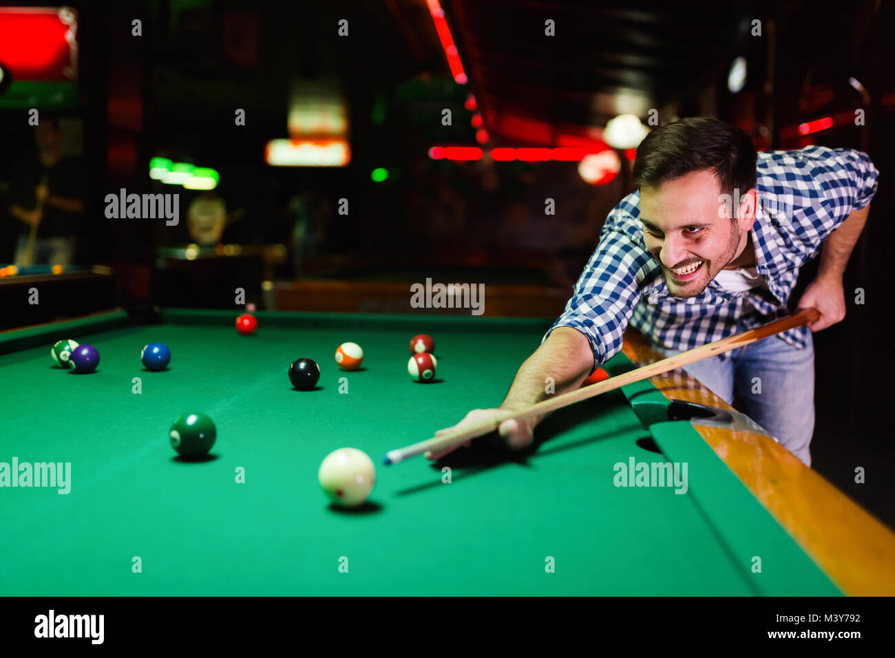 Giovane uomo attraente giocando a biliardo nel bar Foto Stock