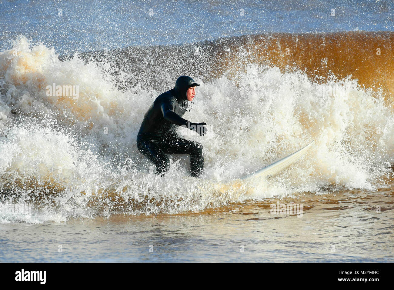 Sidmouth, Devon, Regno Unito. Il 13 febbraio 2018. Regno Unito Meteo. Un surfista godendo le buone condizioni delle onde sotto il sole a Sidmouth nel Devon dopo un burrascoso inizio di giornata. Credito Foto: Graham Hunt/Alamy Live News. Foto Stock