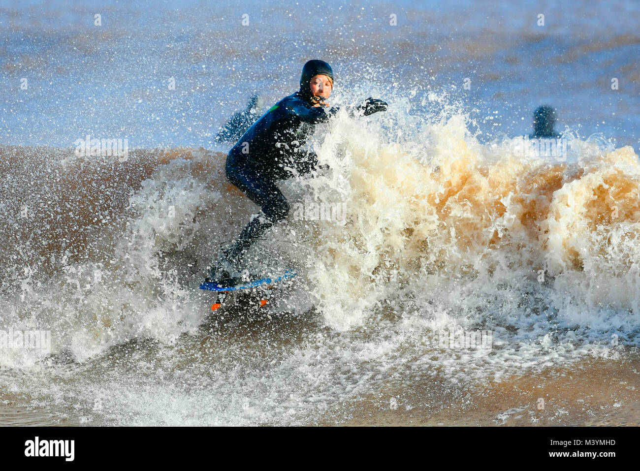 Sidmouth, Devon, Regno Unito. Il 13 febbraio 2018. Regno Unito Meteo. Un surfista godendo le buone condizioni delle onde sotto il sole a Sidmouth nel Devon dopo un burrascoso inizio di giornata. Credito Foto: Graham Hunt/Alamy Live News. Foto Stock