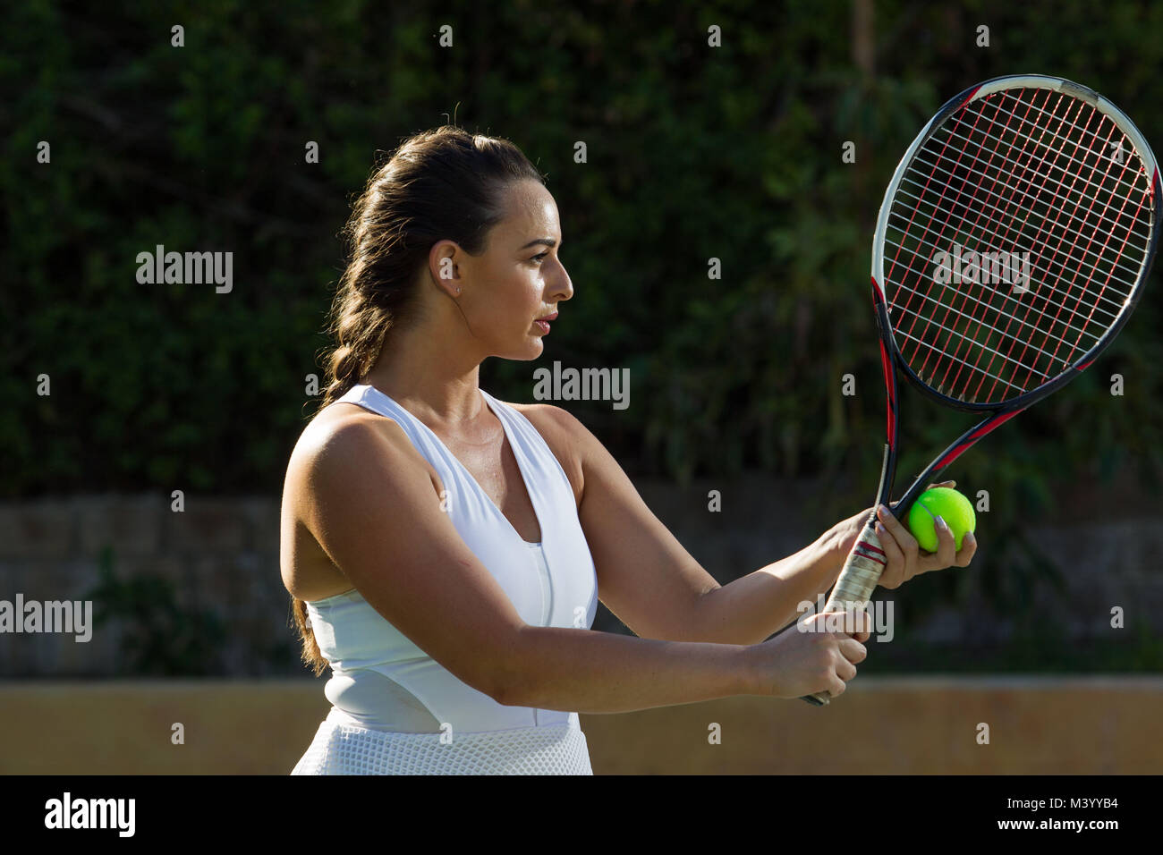 Un giovane giocatore di tennis si prepara a colpire un servire su un campo da tennis in Beverly Hills, la California. Foto di Francesco Specker Foto Stock