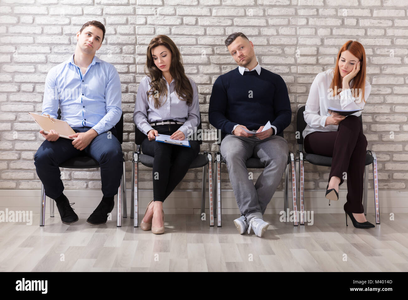 La gente di affari sono annoiarsi mentre è seduto su una sedia in attesa per il colloquio di lavoro in ufficio Foto Stock