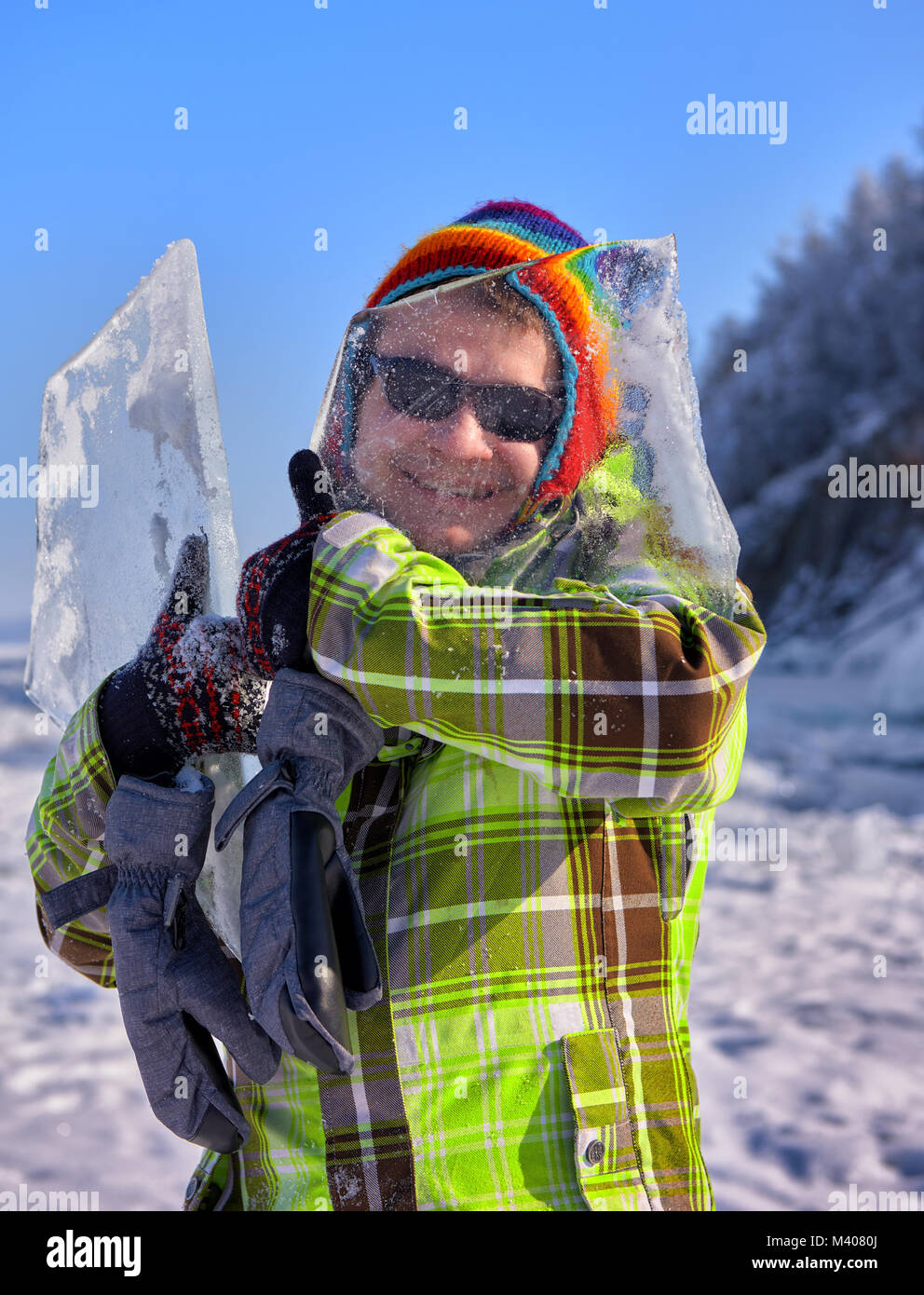 Buon compagno guarda attraverso il ghiaccio sottile di Baikal hummock tenendolo in mano. Positiva la ricreazione e divertimento invernale in Siberia Foto Stock
