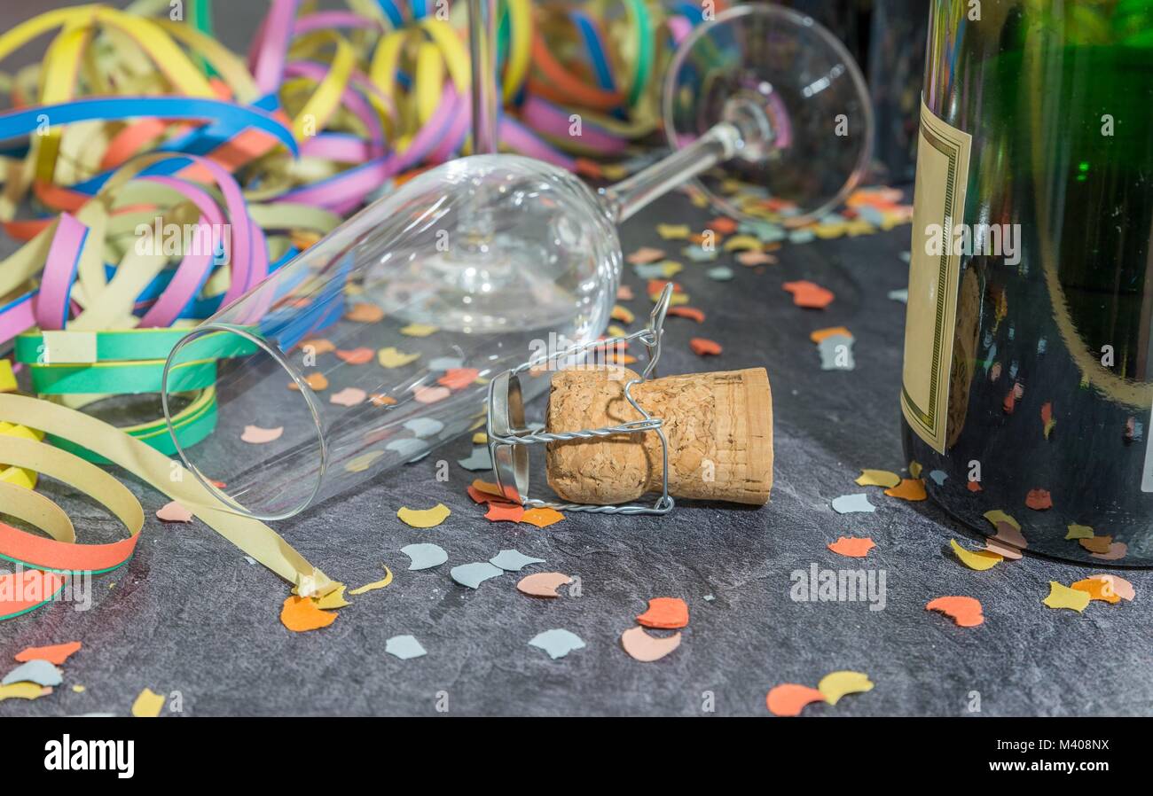 Vetro di champagne e una bottiglia con il carnevale decorazione su una lista Foto Stock