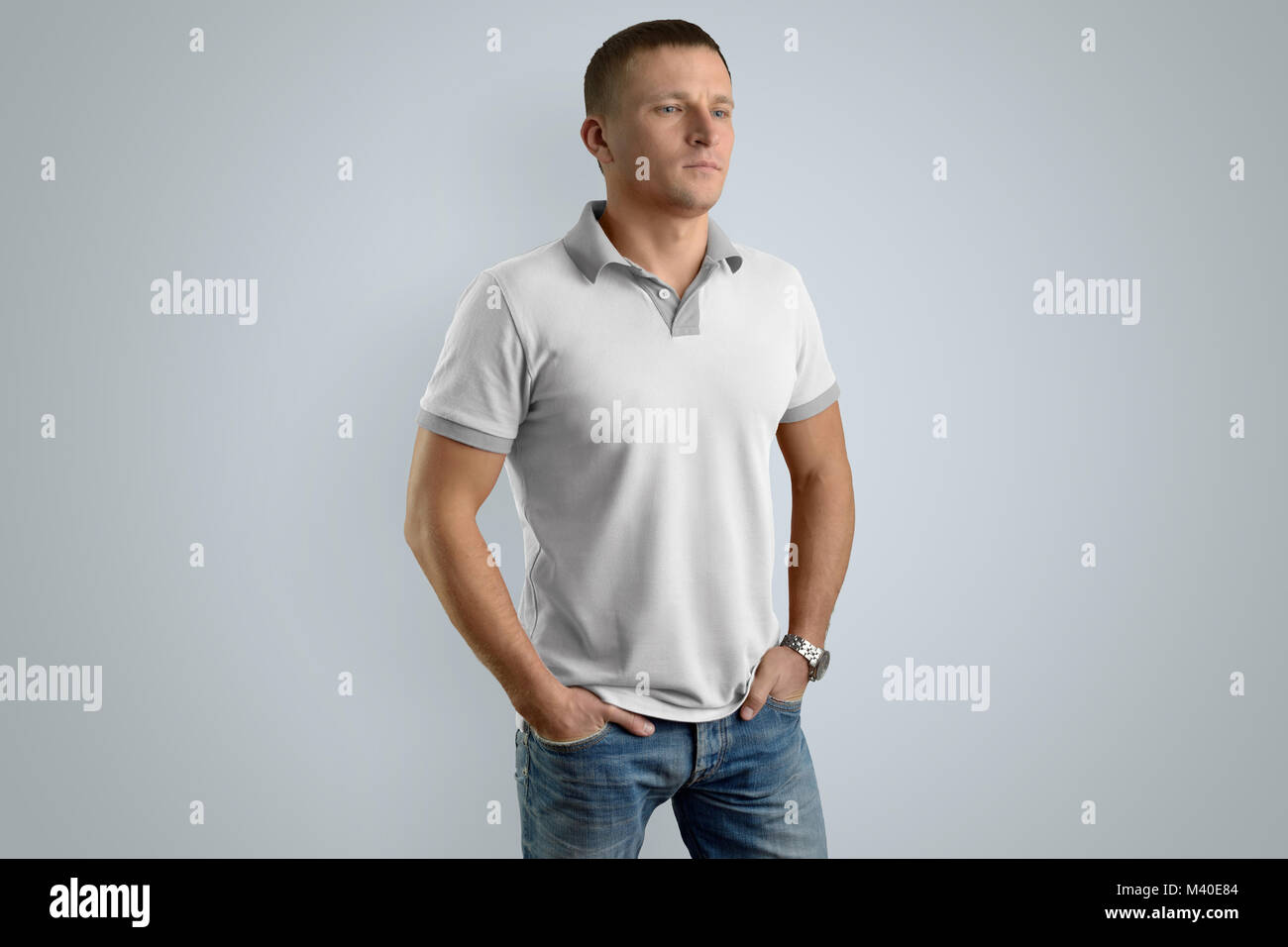 Uomo elegante in bianco Polo shirt e jeans blu con le mani nelle tasche  isolato su sfondo grigio, vista frontale. Mockup per il vostro progetto o l  Foto stock - Alamy