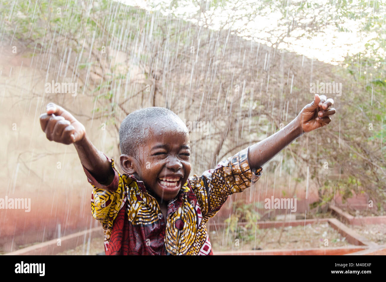 L'acqua è venuta! Etnia africana ragazzino felice di ottenere finalmente un po' di pioggia Foto Stock