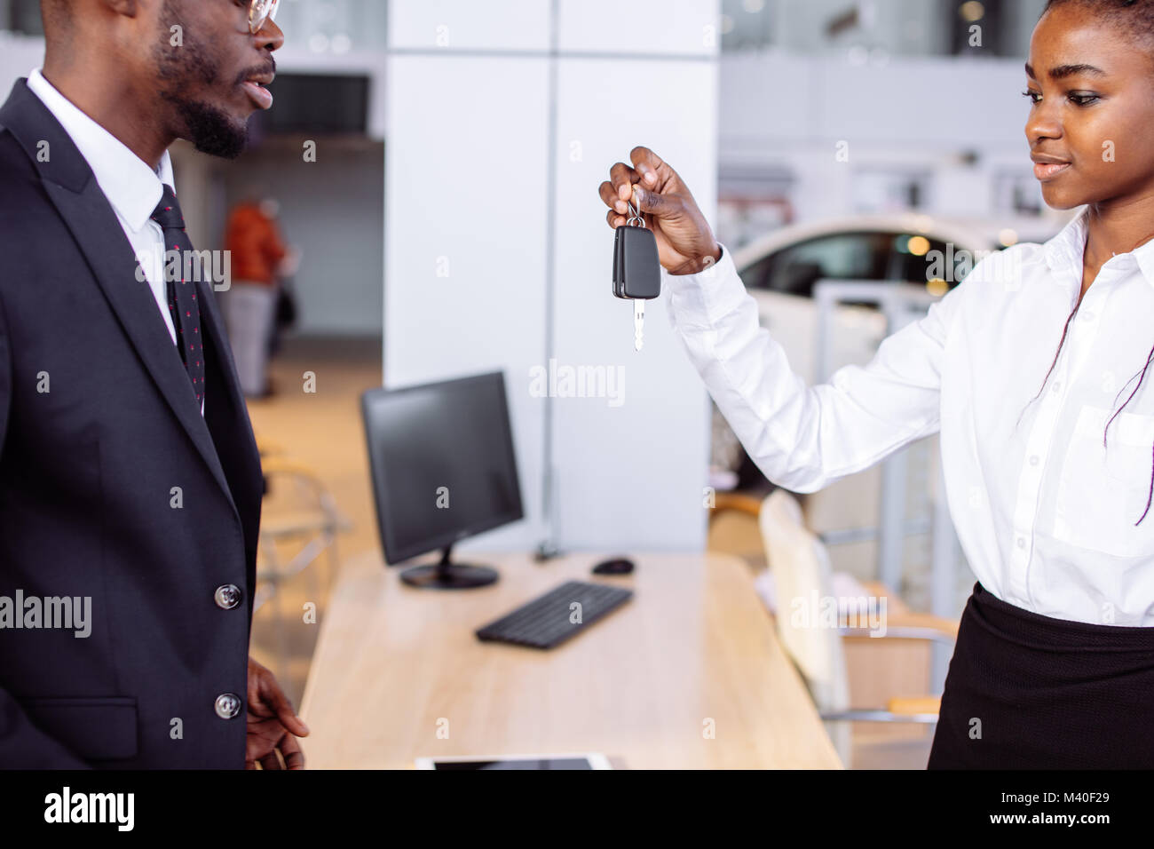 Situazione delle vendite in concessionaria auto, giovane africano coppia ottiene la chiave per la nuova vettura Foto Stock