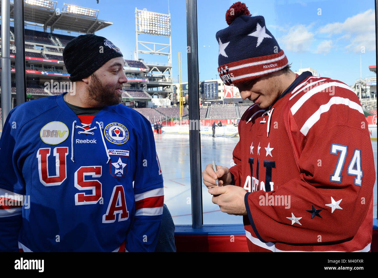 Washington capitelli in avanti John Carlson segni un puck per Michael Caino degli STATI UNITI D'AMERICA Guerrieri veterani feriti squadra di hockey durante una giornata media per il Classico inverno 2015 a cittadini Parco di Washington, D.C. Dic. 31, 2014. La National Hockey League inclusi i veterani feriti hockey club in media giorno insieme con il Chicago Blackhawks e capitelli di Washington. (DoD News foto da EJ Hersom) 141231-D-DB155-002 dal DoD Notizie Foto Foto Stock