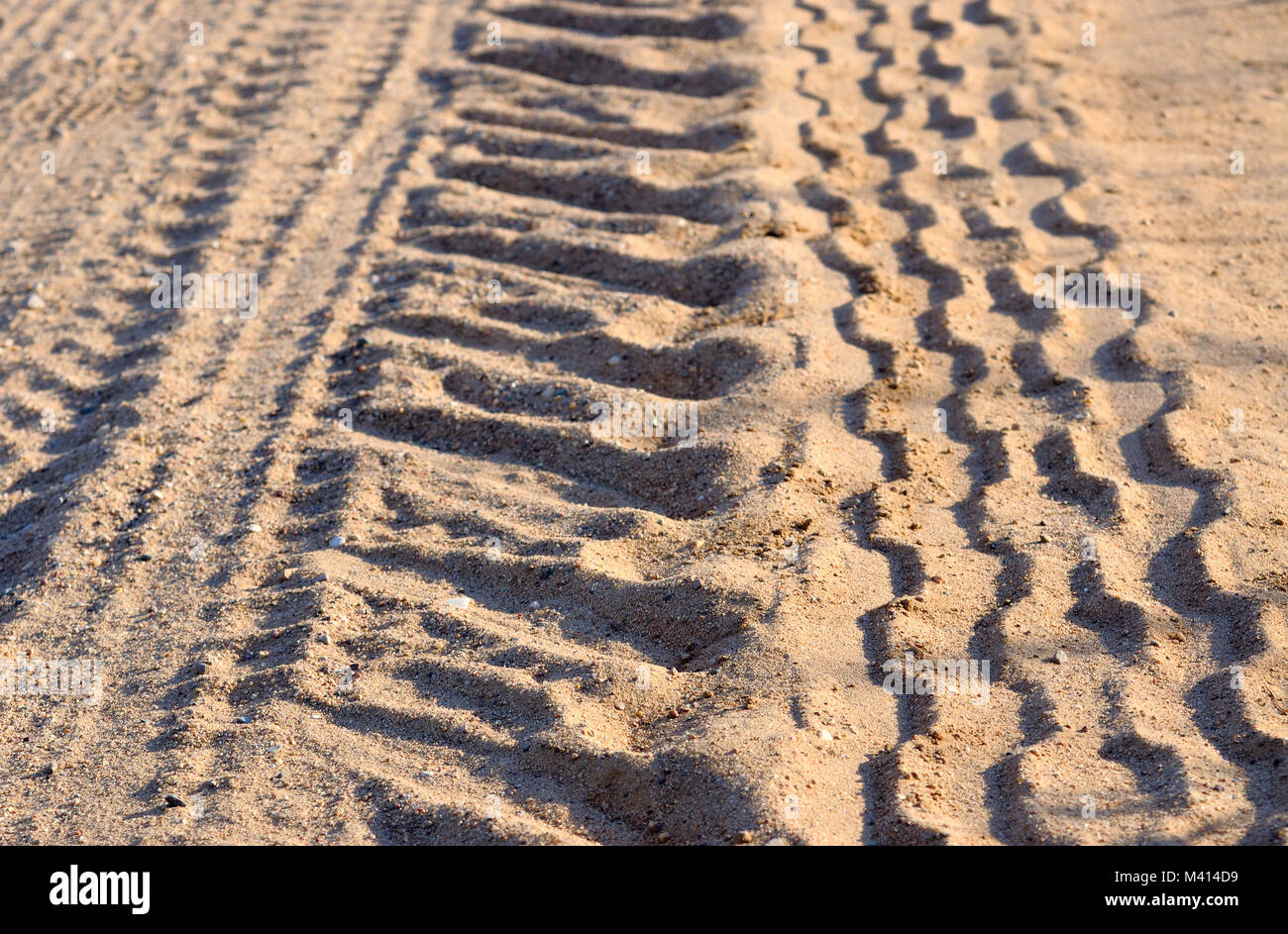 Tracce di pneumatici su una strada di sabbia, illuminata dal sole di setting Foto Stock