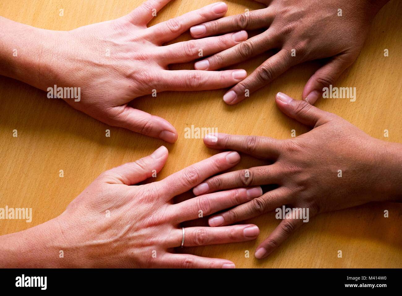 Guardando verso il basso su quattro cinquanta anni di mani femminili sparsi, che giace piatto su una tabella, le due mani sulla sinistra una asiatica di mani e due sulla destra un Foto Stock