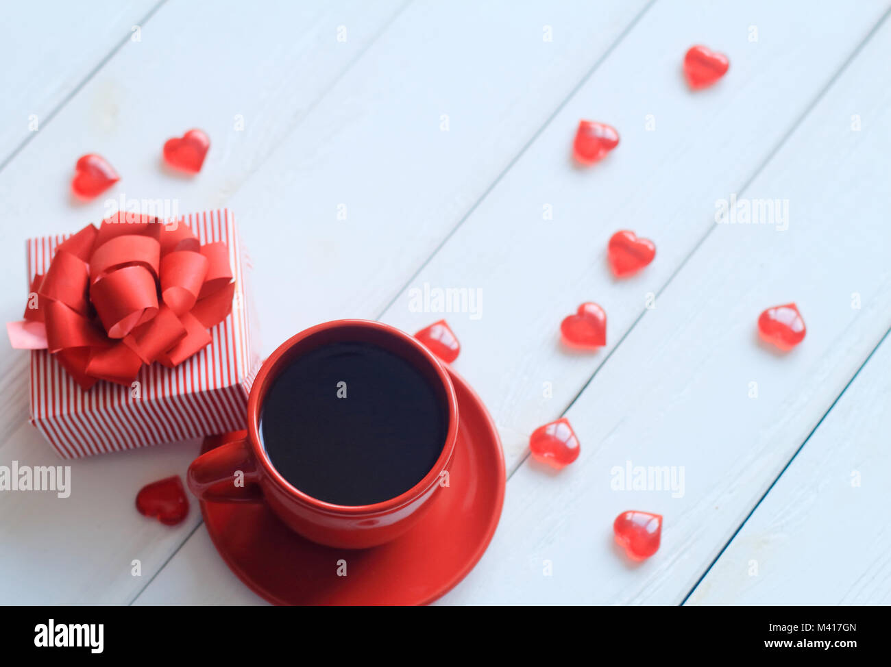 Red tazza di caffè e confezione regalo sul tavolo di legno Foto Stock