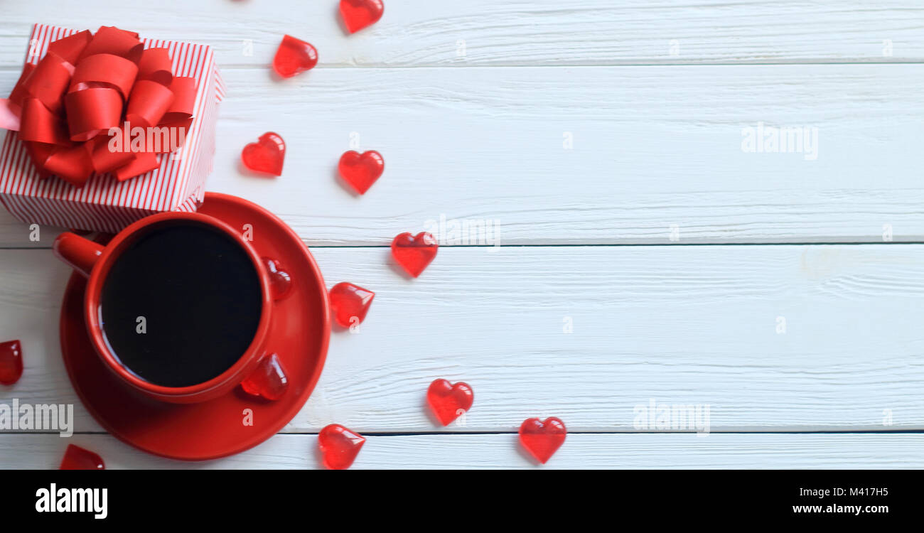 Vista superiore.la tazza di caffè e confezione regalo con nastro rosso su una tavola di legno. Foto Stock