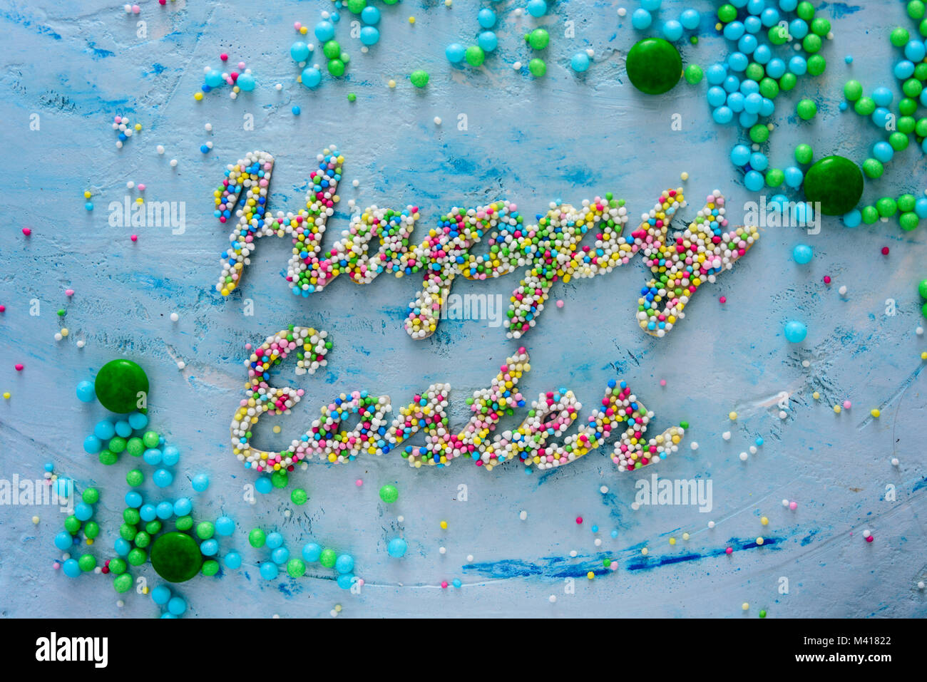 Parole Felice Pasqua fatta di caramelle colorate in blu su sfondo pastello Foto Stock