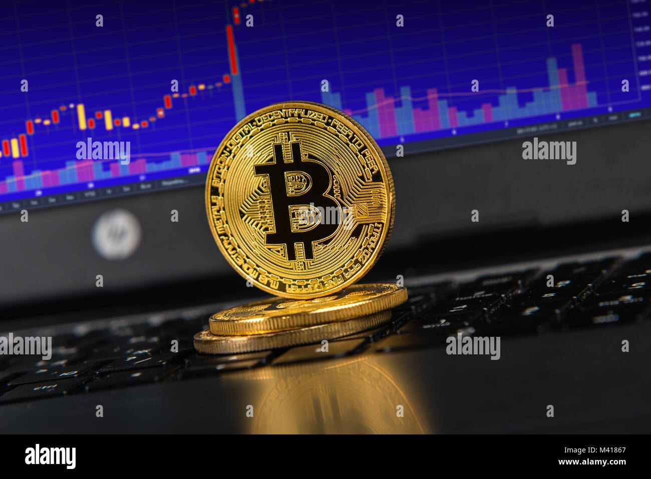 Bitcoins sulla tastiera del notebook, il grafico blu sullo schermo Foto Stock