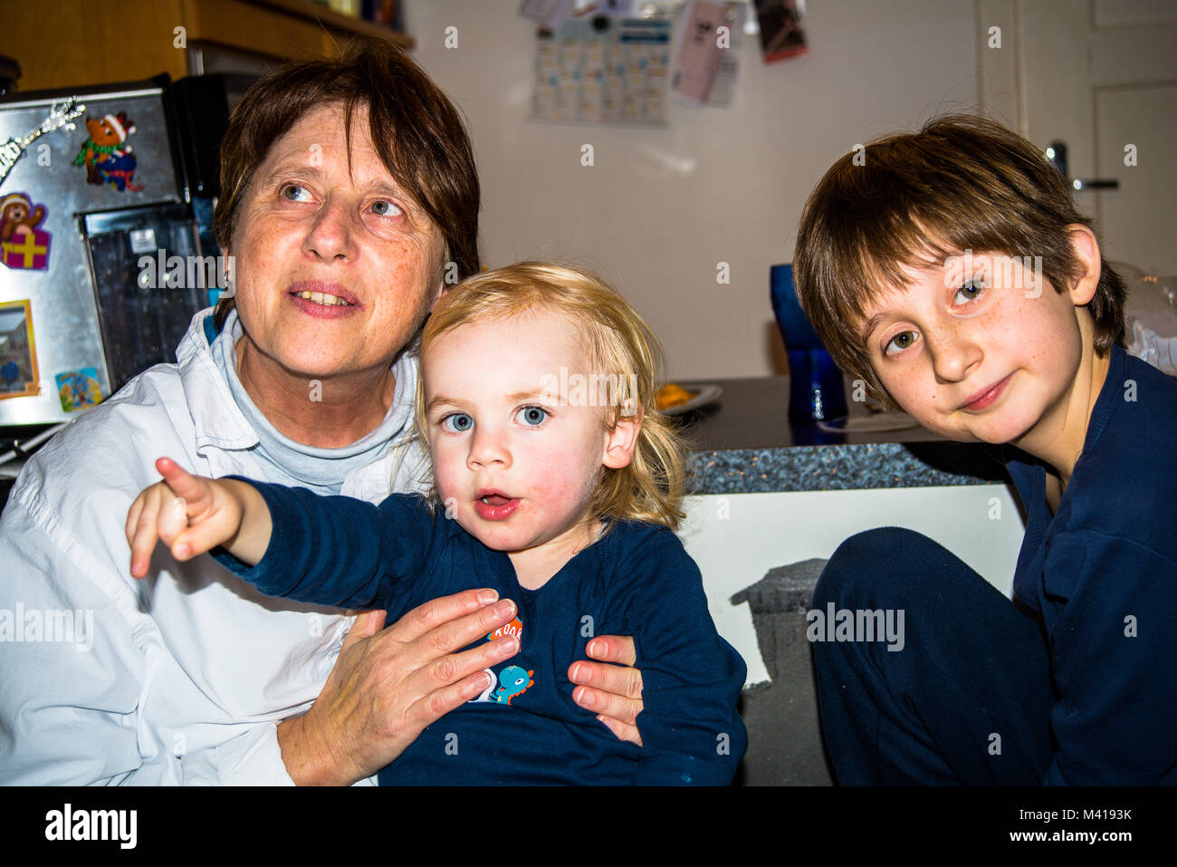 Neuoetting,Germany-Feb 12,2018: una donna tiene a suo nipote mentre suo figlio guarda la fotocamera durante una riunione di famiglia Foto Stock