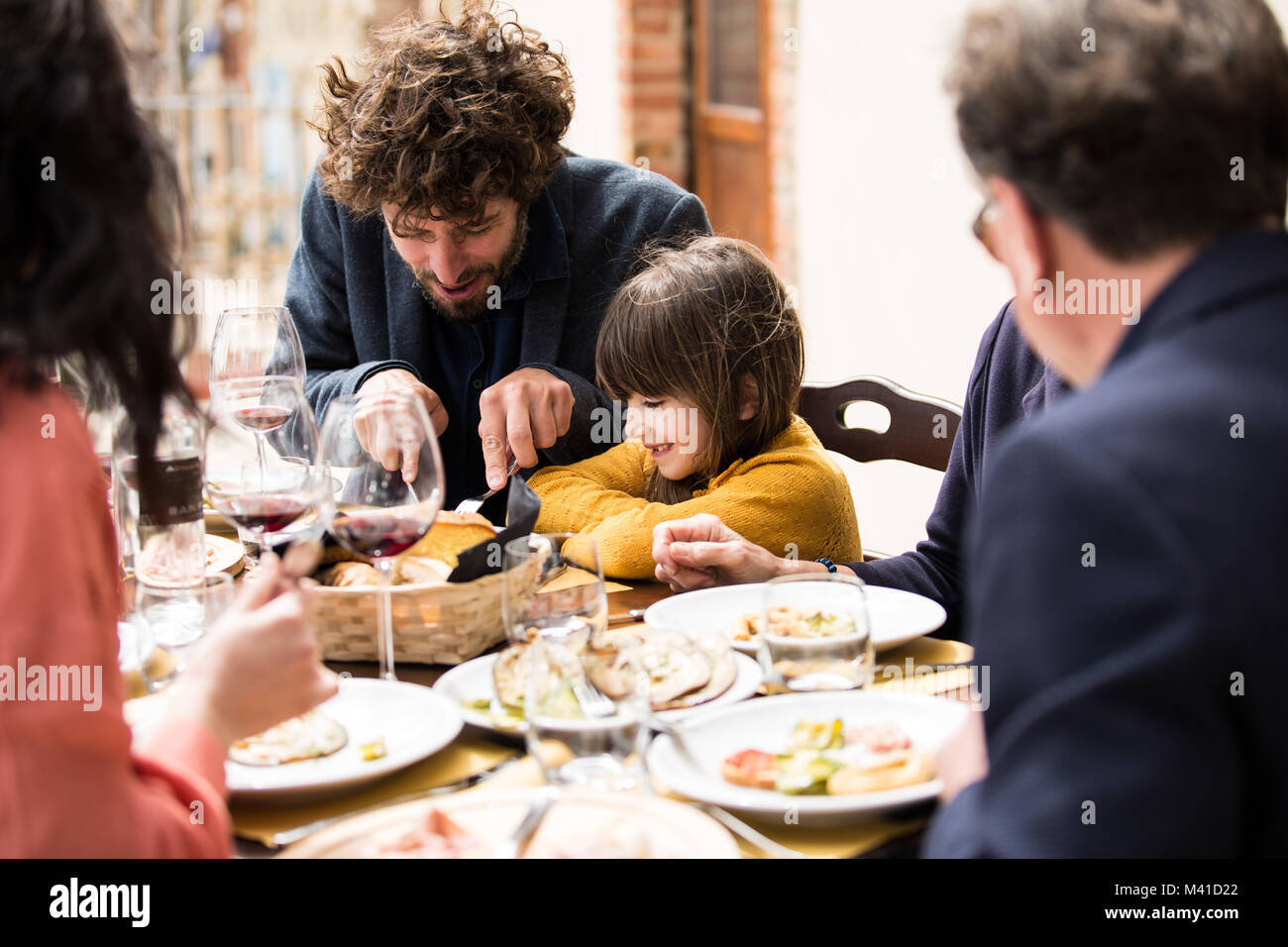 Padre aiutando la figlia tagliare il suo cibo Foto Stock