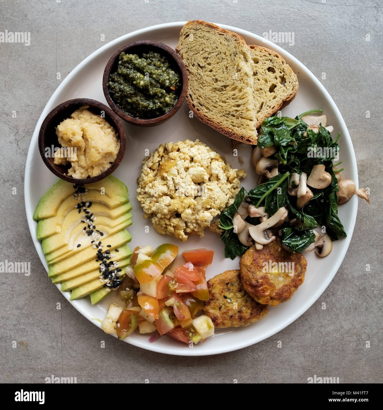 Vegan tofu con avocado, pane, verdure e fonte di close-up su una piastra. Foto Stock
