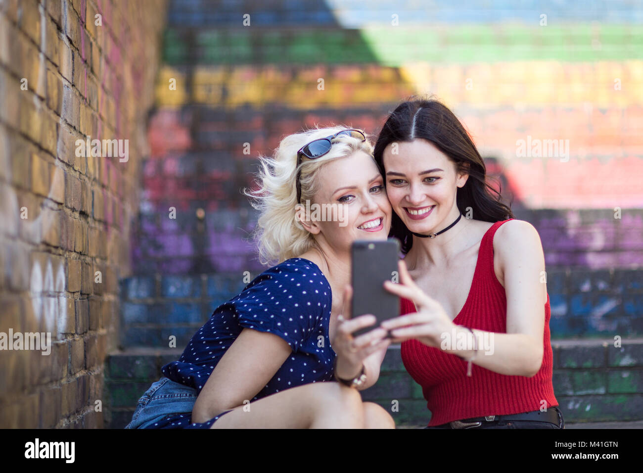 Amici di sesso femminile prendendo selfie in città urbana Foto Stock