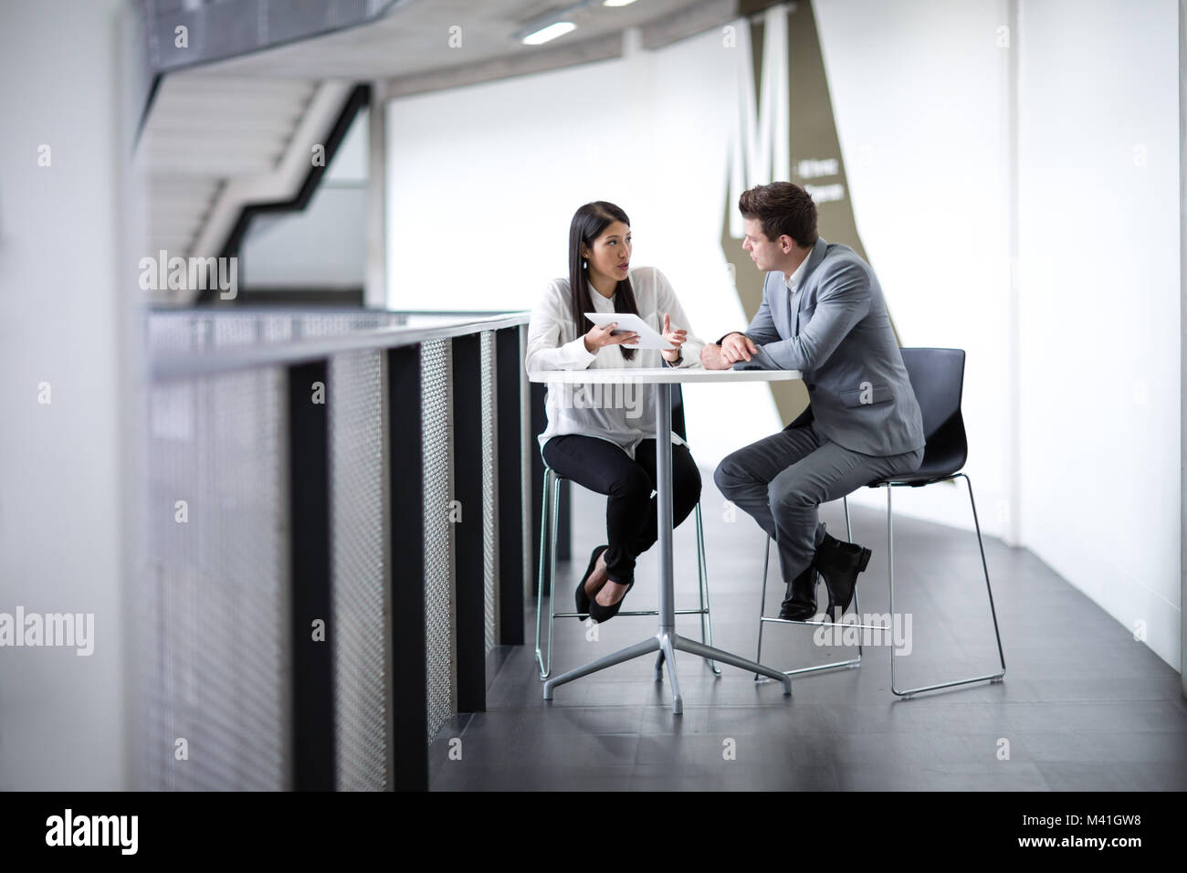 I colleghi in un ambiente informale riunione aziendale utilizzando una tavoletta digitale Foto Stock