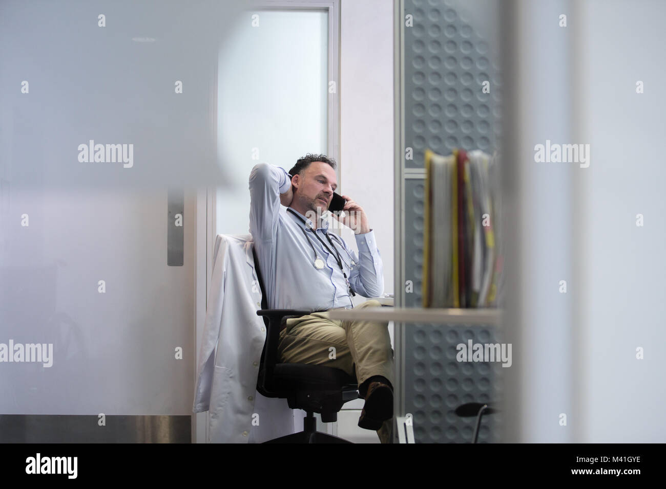 Sottolineato medico sul telefono nel suo ufficio Foto Stock