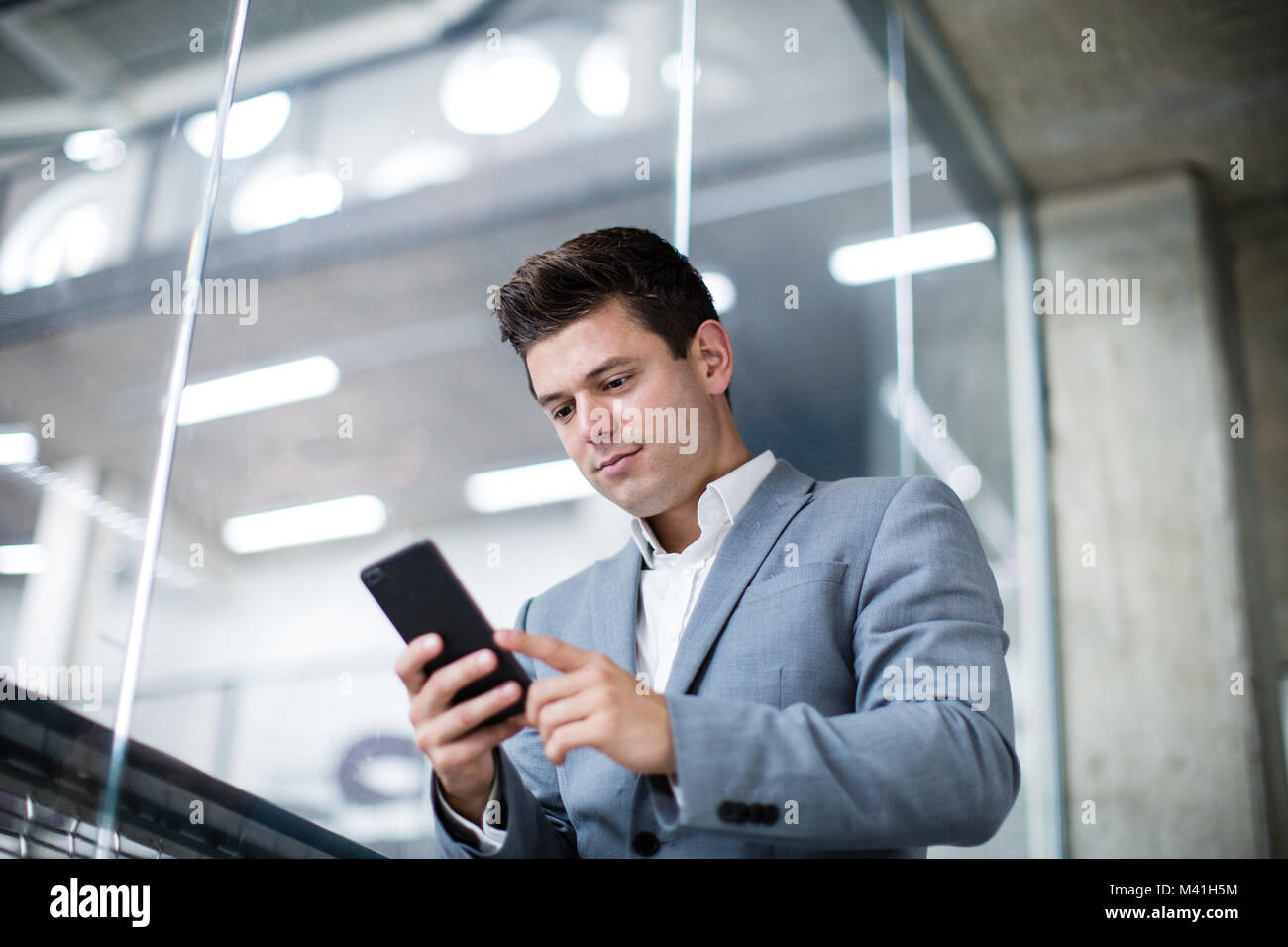 Imprenditore utilizza lo smartphone in un ufficio Foto Stock