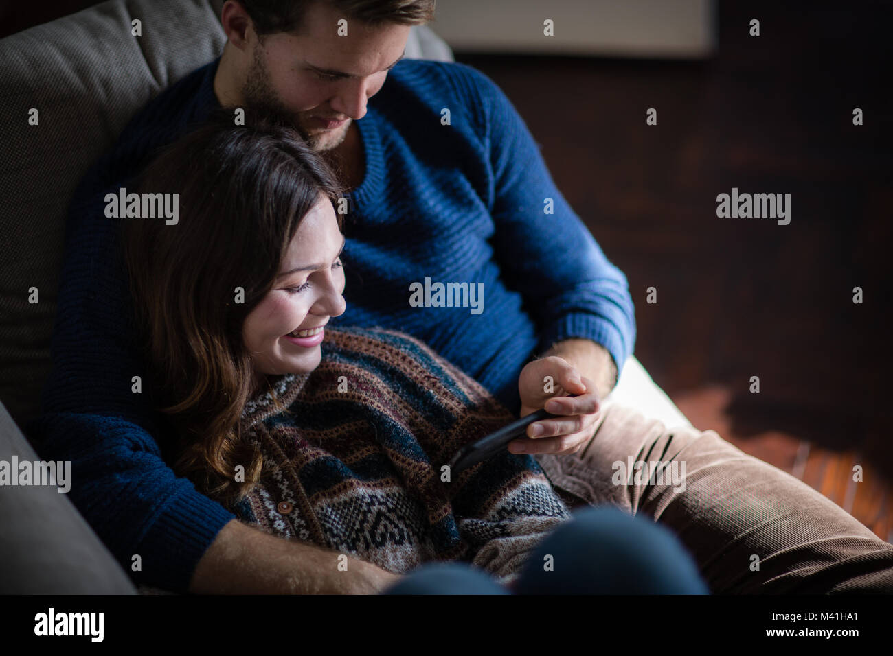 Giovane guardando smartphone sul divano Foto Stock