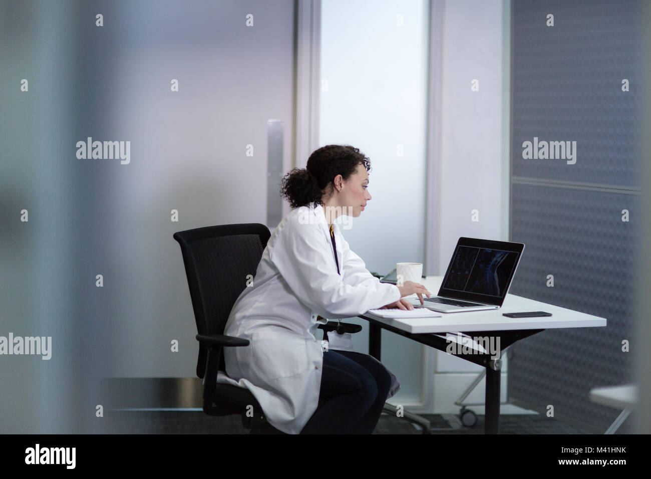 Donne Medico guardando i risultati dei raggi x sul computer portatile Foto Stock