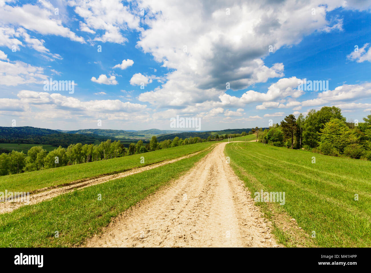 Blu cielo nuvoloso su verdi colline e strade di campagna Foto Stock