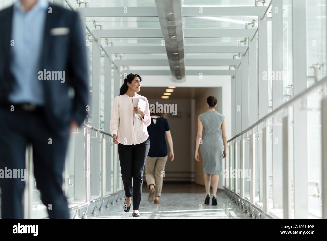 Femmina executive business a piedi attraverso ufficio indaffarato corridoio Foto Stock