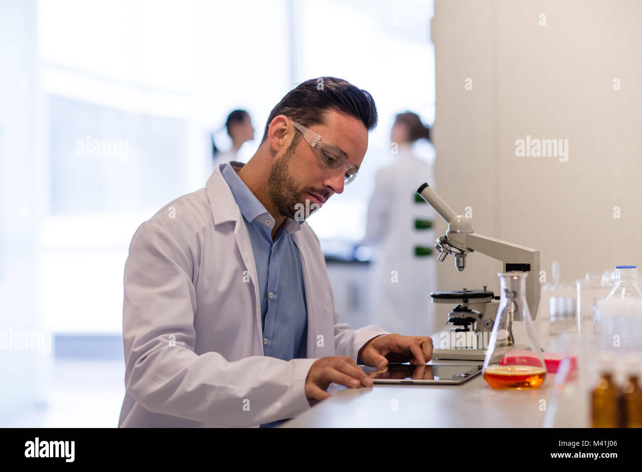 Scienziato maschio guardando i risultati di un esperimento su tavoletta digitale Foto Stock