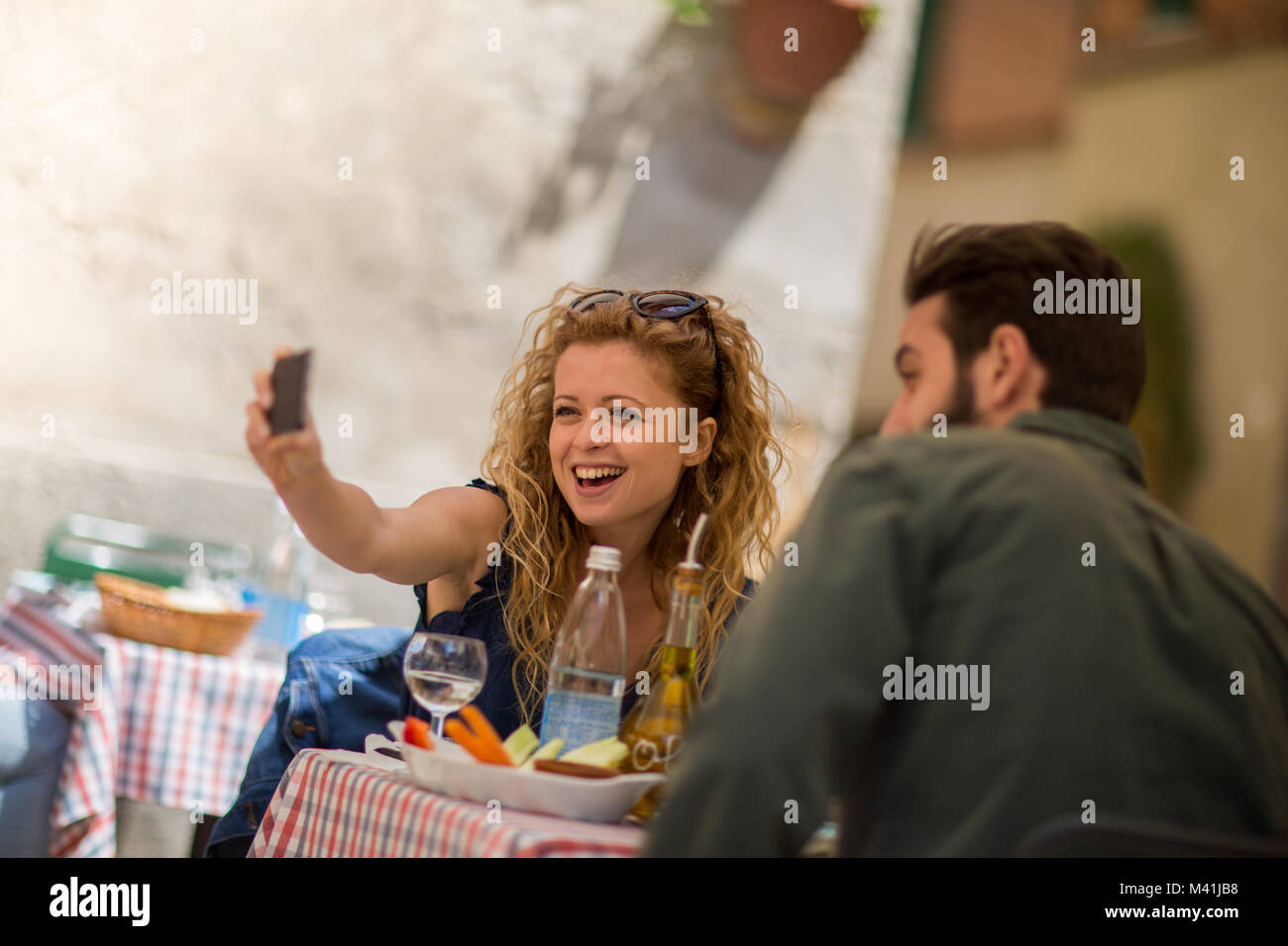 Coppia giovane mangiare alfresco prendendo un selfie Foto Stock
