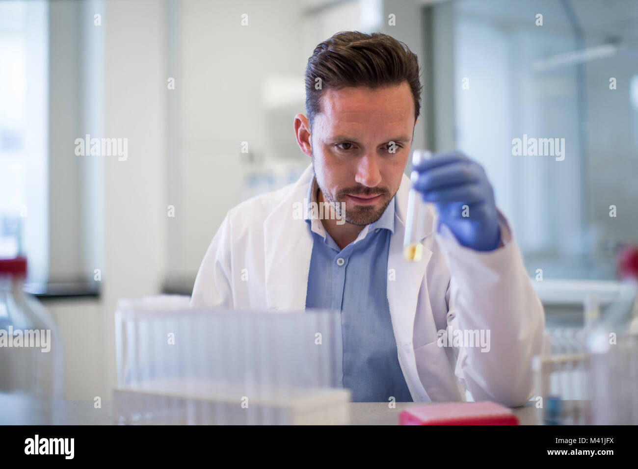 Scienziato maschio guardando al tubo di prova in un laboratorio Foto Stock
