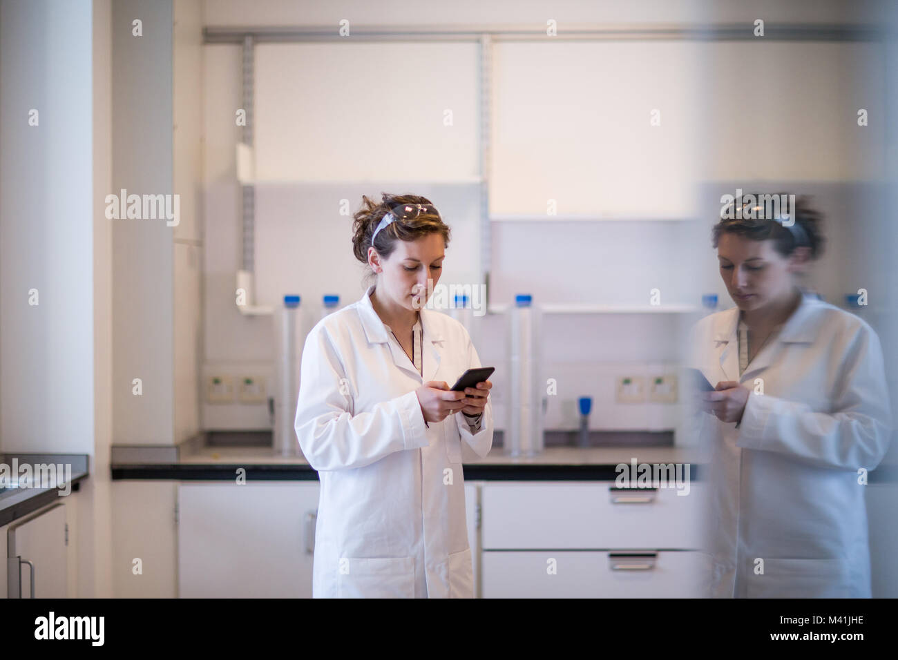 Donna scienziato utilizza lo smartphone in laboratorio Foto Stock