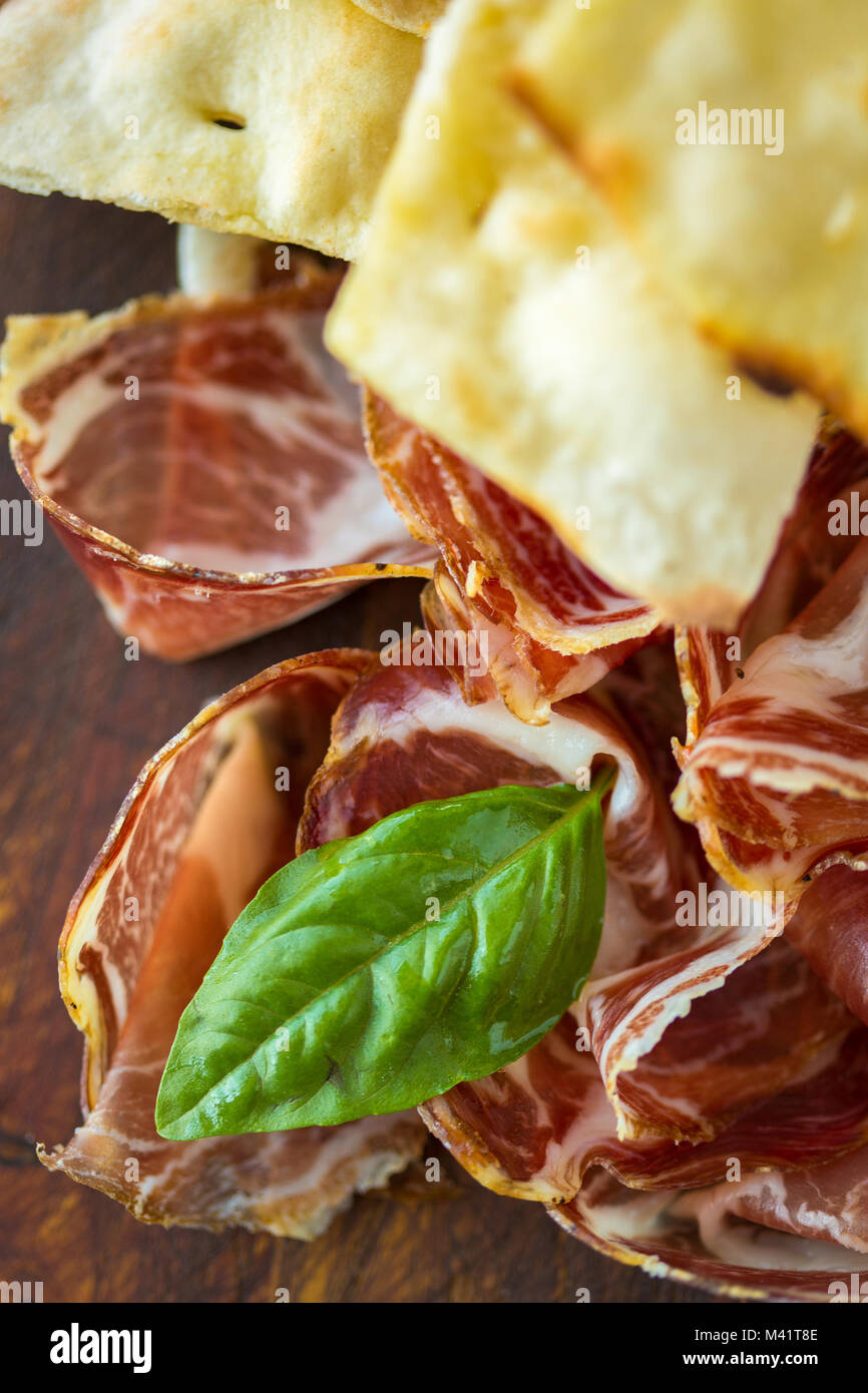 Il prosciutto casalingo e basilico su una tavola di legno Foto Stock