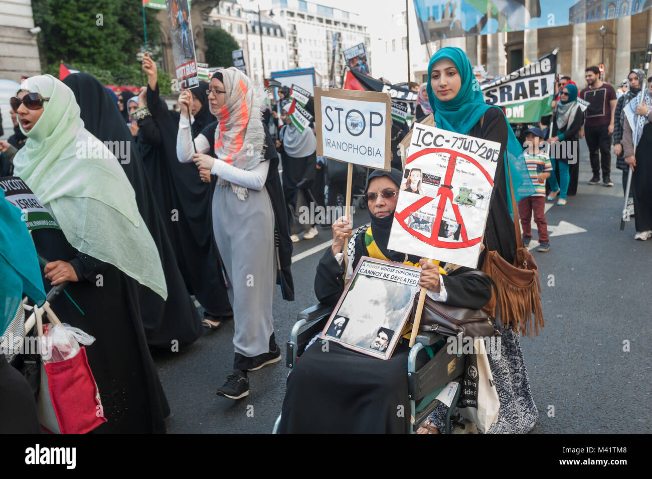 Una donna su una sedia a rotelle ha una cornice per una foto di Khomeini e una targhetta 'Stop Iranophobia' su di Al Quds giorno marzo a Londra. Foto Stock