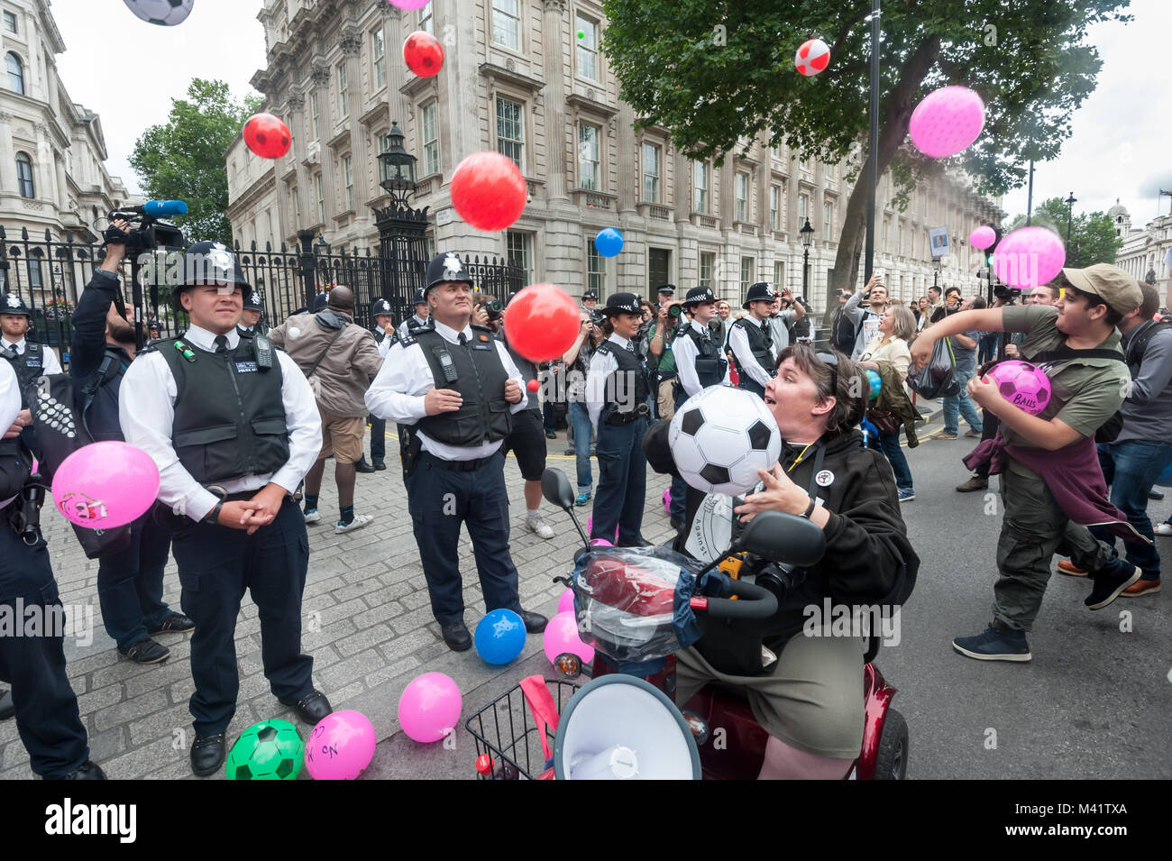 Paula Peters di DPAC e altri manifestanti lanciare palle con messaggi per la governent dentro Downing St in corrispondenza dei Disabili contro i tagli "Balls al bilancio" protesta. Foto Stock