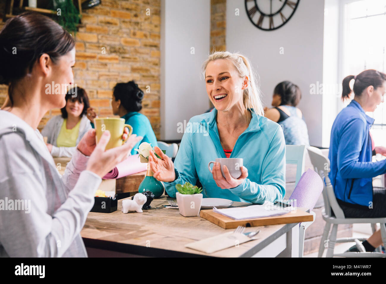 Le donne sono seduti a un tavolo in un cafe, socializzare sorseggiando caffè e tè. Foto Stock