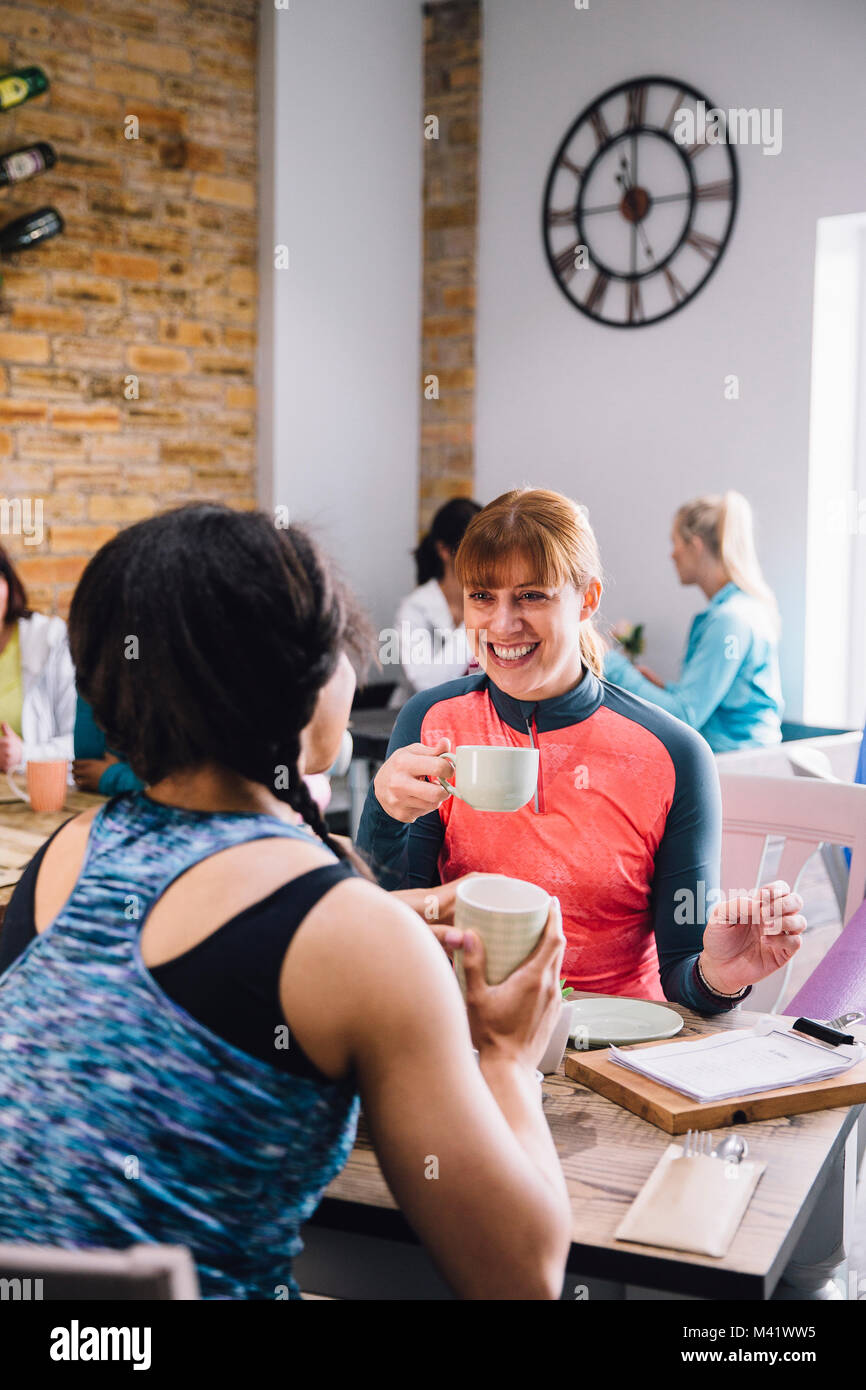 Le donne sono seduti a un tavolo in un cafe, socializzare sorseggiando caffè e tè. Foto Stock