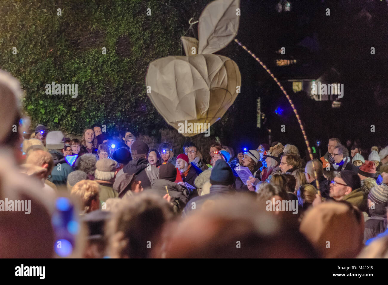 A forma di mela lanterna di carta portati dalla folla attraverso la strada a un wassail o tradizionale winter festival apple, Stoke Gabriel, Devon, Regno Unito. Jan 2018. Foto Stock