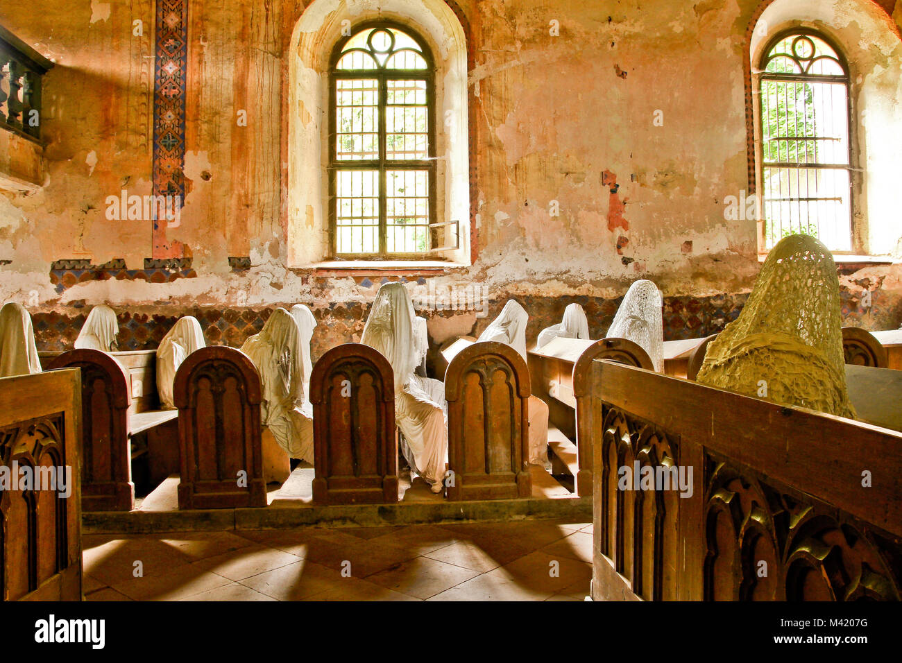 La foto dall'interno del vecchio abbandonato, quasi distrutta chiesa nella Repubblica Ceca. All'interno sono le statue dei credenti fantasmi. Foto Stock