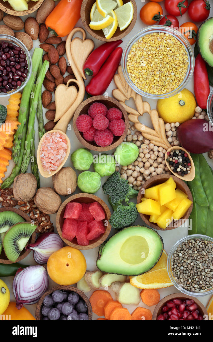 Cibo sano per il benessere concetto con frutta, verdura, erbe e legumi, cereali, noci, semi con grani di pepe e sale himalayano in lovespoons. Sup Foto Stock